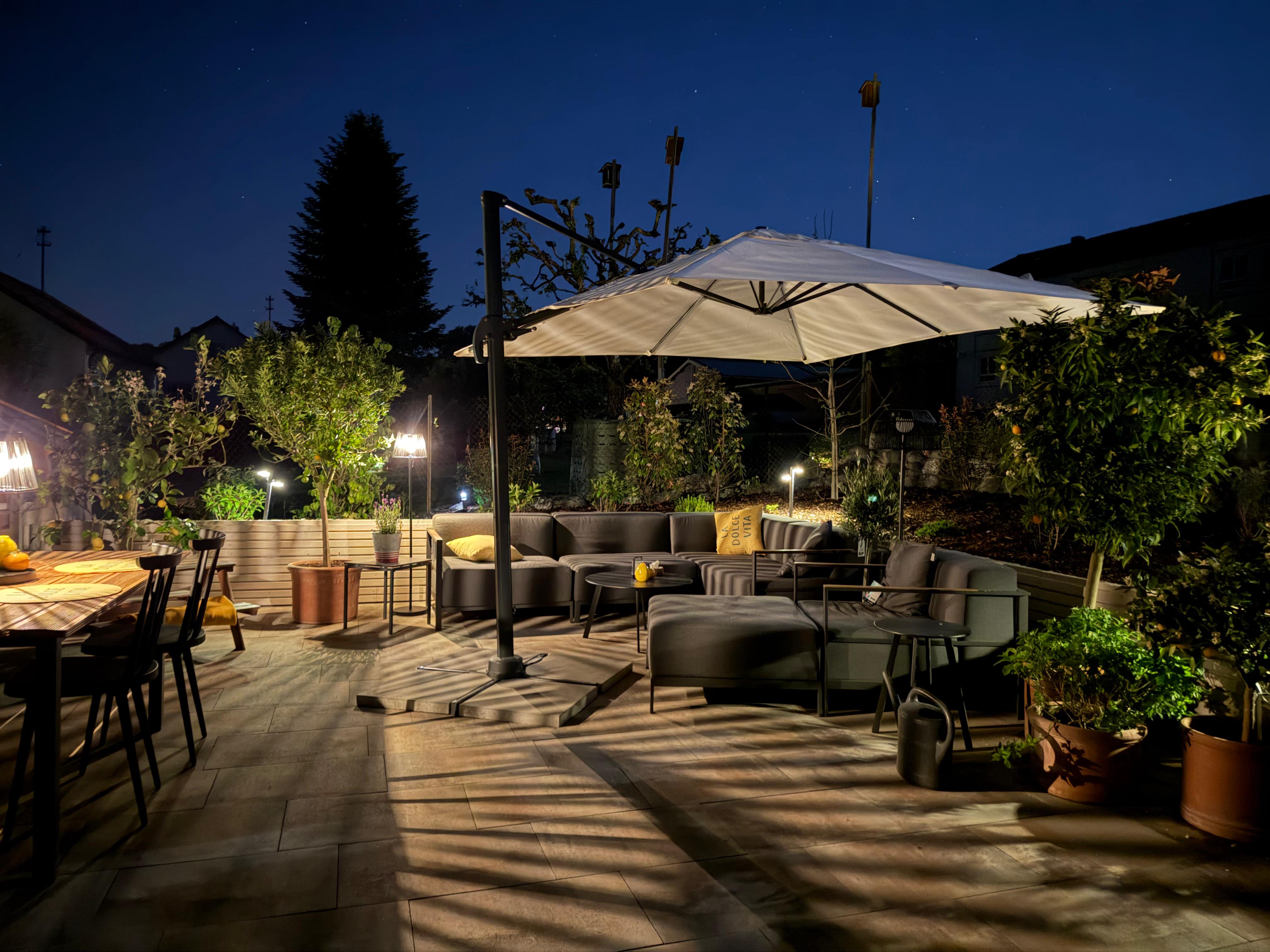 Stimmungsvoll beleuchtete Terrasse und Gartenanlage am Abend