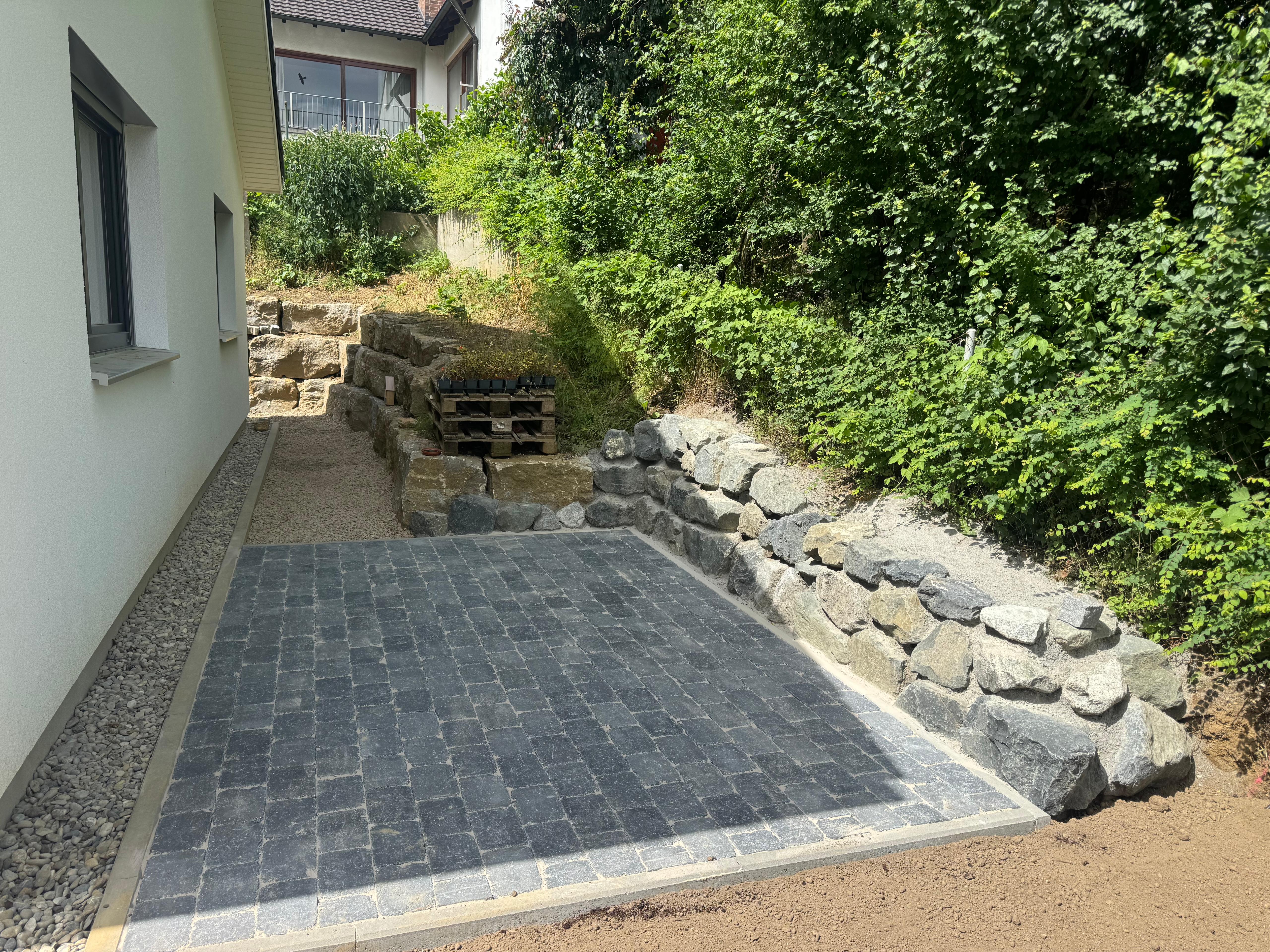 Neu angelegte Pflasterfläche mit Naturstein-Stützmauer